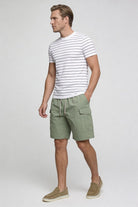 Men’s sage green utility cargo shorts with drawstring waist and side cargo pockets in lightweight fabric model shoot