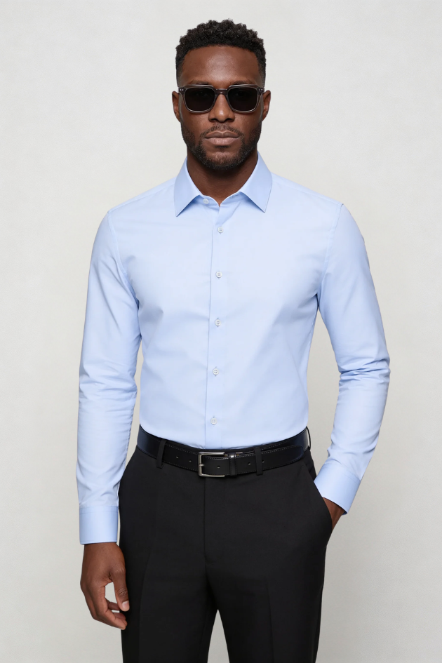Man wearing a light blue dress shirt and black pants against a plain background