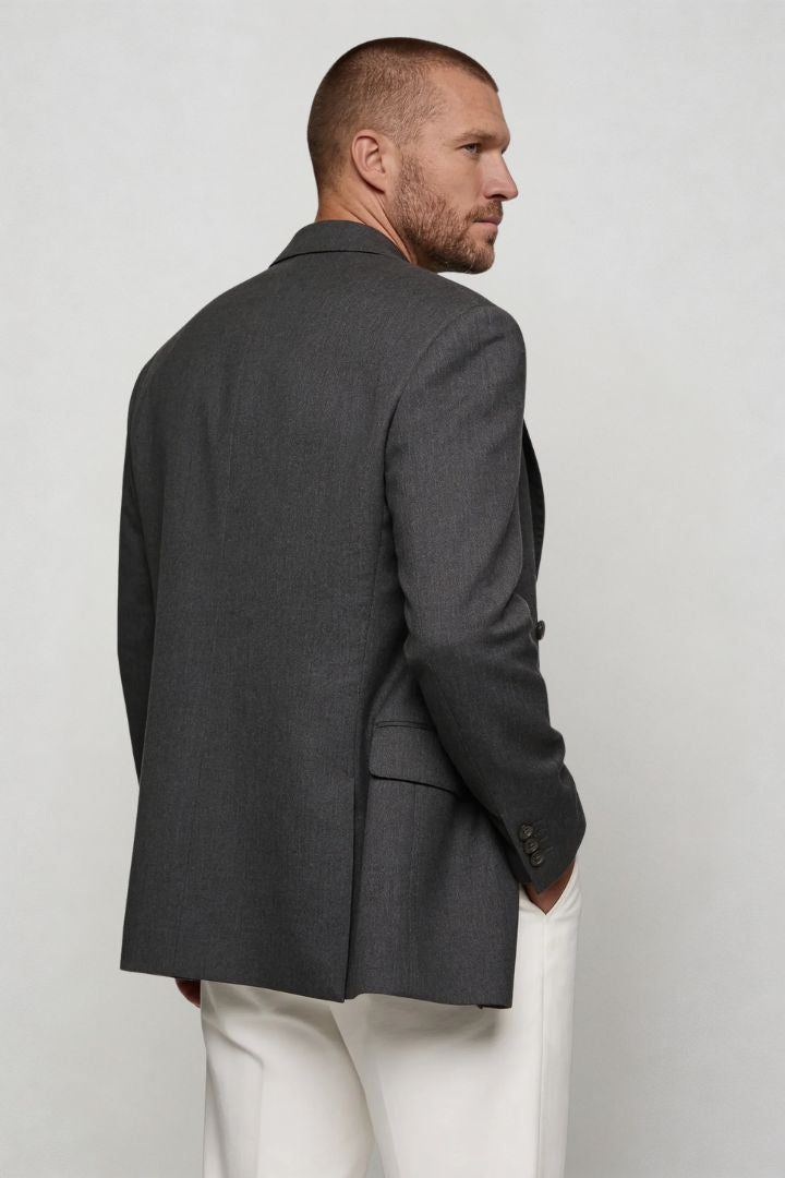 Man wearing a gray blazer and white pants against a plain background